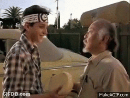 Two Men Are Shaking Hands In Front Of A Car In A Movie . GIF