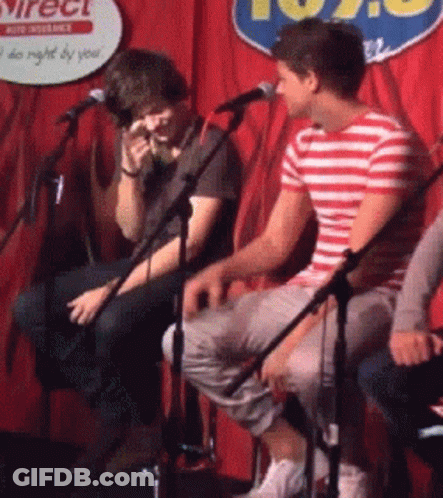 Two Men Are Singing Into Microphones In Front Of A Sign That Says 102.9 GIF