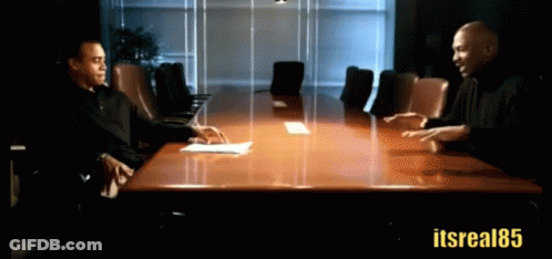 Two Men Are Sitting At A Conference Table With The Hashtag Itsreal85 GIF