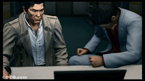 Two Men Are Sitting At A Desk In Front Of A Computer GIF