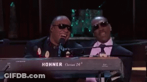 Two Men Are Sitting At A Keyboard And One Of Them Is Wearing Sunglasses . GIF