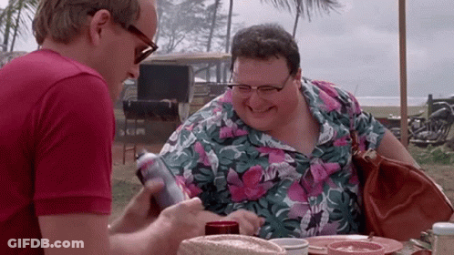 Two Men Are Sitting At A Table And One Is Holding A Can Of Soda GIF