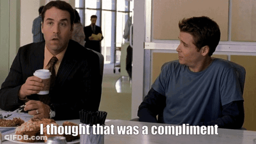 Two Men Are Sitting At A Table And One Of Them Is Saying " I Thought That Was A Compliment " GIF