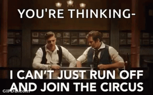Two Men Are Sitting At A Table Drinking Whiskey And Talking To Each Other In A Bar . GIF