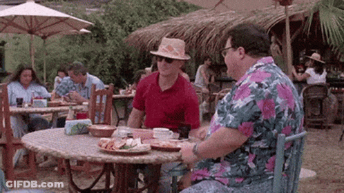 Two Men Are Sitting At A Table Eating Food In A Restaurant . GIF