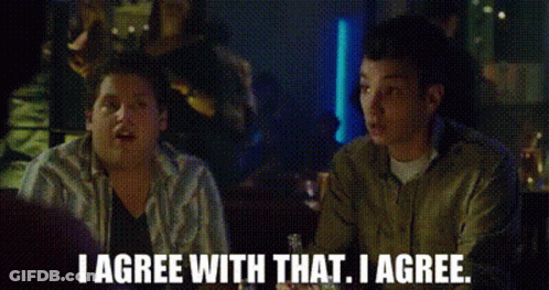 Two Men Are Sitting At A Table In A Bar And Talking To Each Other . GIF
