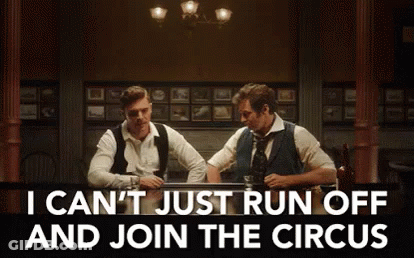 Two Men Are Sitting At A Table In A Dark Room Talking To Each Other . GIF