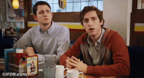 Two Men Are Sitting At A Table In A Diner With A Box Of Kellogg 'S Cereal On It GIF
