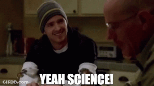 Two Men Are Sitting At A Table In A Kitchen And One Of Them Is Smiling And Saying `` Yeah Science '' . GIF