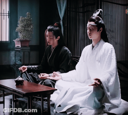 Two Men Are Sitting At A Table In A Room . One Of The Men Is Wearing A White Robe . GIF