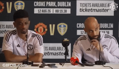 Two Men Are Sitting At A Table In Front Of A Sign That Says Ticketmaster GIF