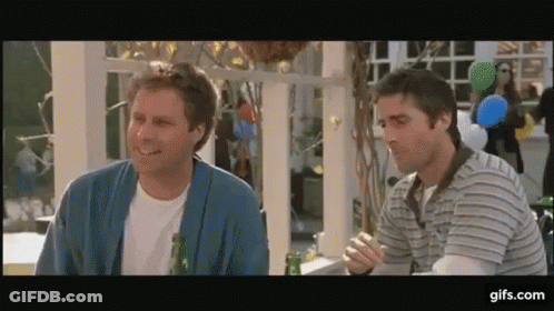 Two Men Are Sitting At A Table With A Bottle Of Beer And Smiling . GIF