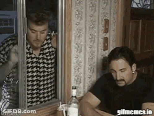 Two Men Are Sitting At A Table With A Bottle Of Vodka And Talking On A Cell Phone . GIF
