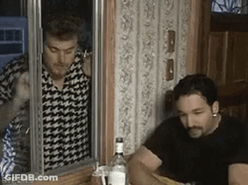 Two Men Are Sitting At A Table With A Bottle Of Vodka In Front Of Them And One Of Them Is Smoking A Cigarette . GIF