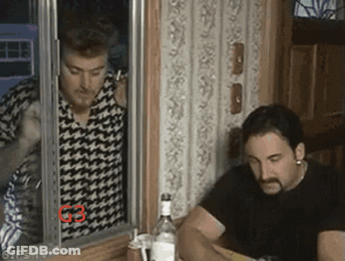 Two Men Are Sitting At A Table With A Bottle Of Vodka In Front Of Them And The Number G3 Is On The Wall GIF