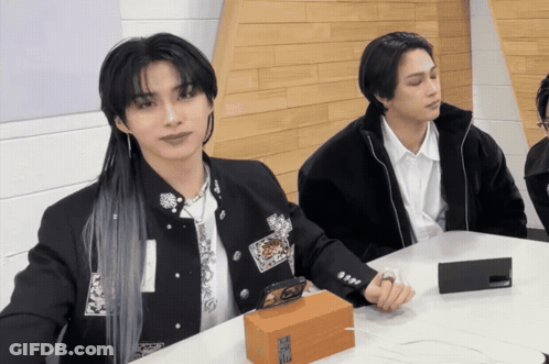 Two Men Are Sitting At A Table With A Box That Says ' Samsung ' On It In Front Of Them GIF