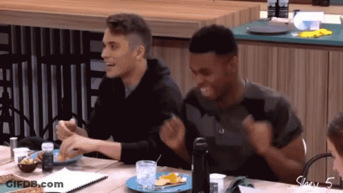 Two Men Are Sitting At A Table With A Plate Of Food And A Bottle Of Water GIF