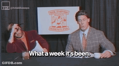 Two Men Are Sitting At A Table With A Sign That Says Southpaw Regional Wrestling GIF