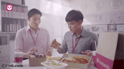 Two Men Are Sitting At A Table With Boxes Of Food And A Bag That Says Foodpanda On It GIF