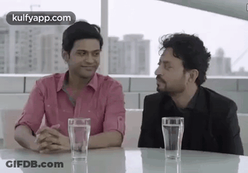 Two Men Are Sitting At A Table With Glasses Of Water In Front Of Them . GIF