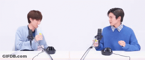 Two Men Are Sitting At A Table With Microphones And Headphones . GIF
