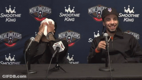 Two Men Are Sitting At A Table With Microphones In Front Of Smoothie King Advertisements GIF