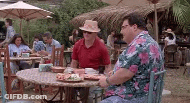 Two Men Are Sitting At A Table With Plates Of Food In Front Of Them . GIF