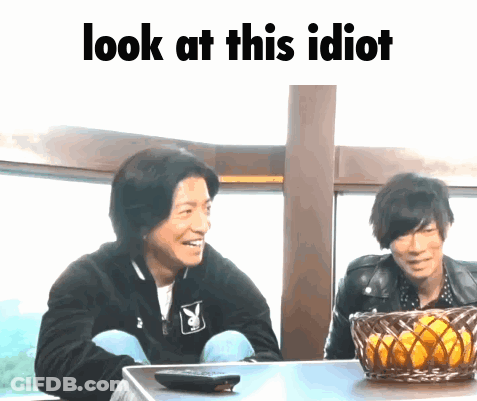Two Men Are Sitting At A Table With The Words Look At This Idiot Written Above Them GIF