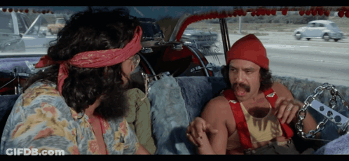 Two Men Are Sitting In A Car And One Has A Bandana On His Head That Says ' Hippie ' On It GIF