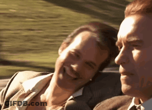 Two Men Are Sitting In A Car And Smiling At Each Other . GIF