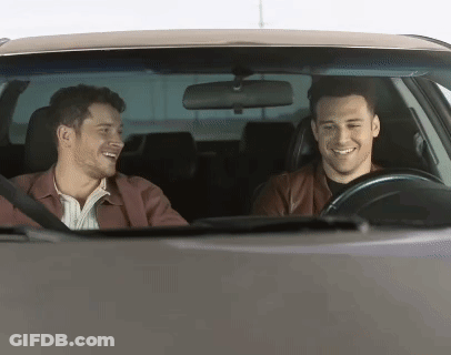 Two Men Are Sitting In A Car Laughing And Smiling GIF