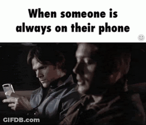 Two Men Are Sitting In A Car Looking At Their Phones And The Caption Says When Someone Is Always On Their Phone GIF