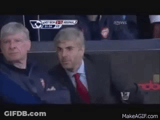 Two Men Are Sitting In A Stadium Watching A Soccer Game And One Of Them Is Wearing A Suit And Tie . GIF