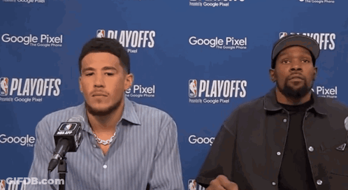 Two Men Are Sitting In Front Of A Google Pixel Sign GIF