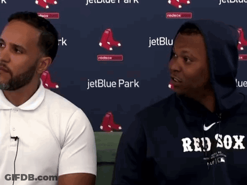 Two Men Are Sitting In Front Of A Jetblue Park Banner GIF