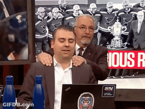 Two Men Are Sitting In Front Of A Laptop That Says Snv GIF