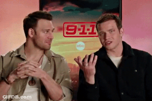 Two Men Are Sitting In Front Of A Poster That Says 911 GIF