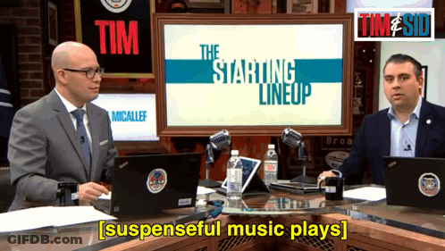 Two Men Are Sitting In Front Of A Screen That Says The Starting Lineup On It GIF