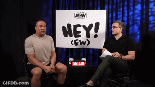 Two Men Are Sitting In Front Of A Sign That Says Hey ( Ew ) GIF