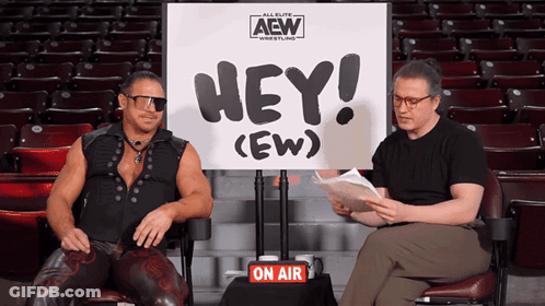 Two Men Are Sitting In Front Of A Sign That Says Hey ( Ew ) GIF