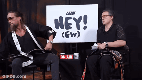 Two Men Are Sitting In Front Of A Sign That Says Hey ( Ew ) GIF
