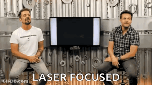 Two Men Are Sitting In Front Of A TV And The Words Laser Focused Are Visible GIF