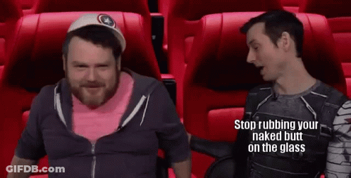 Two Men Are Sitting In Red Seats In A Movie Theater Talking . GIF