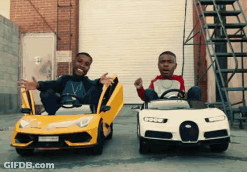 Two Men Are Sitting In Toy Cars With Their Doors Open And One Of Them Has A License Plate That Says ' Sd ' On It GIF