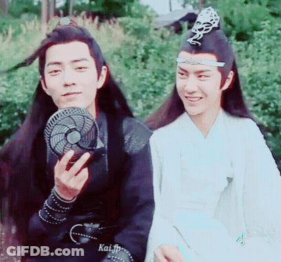 Two Men Are Sitting Next To Each Other And One Of Them Is Holding A Fan In His Hand . GIF