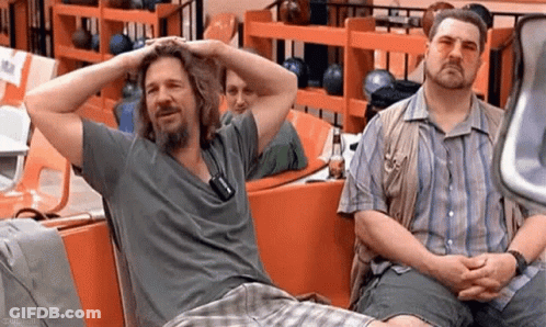 Two Men Are Sitting Next To Each Other In A Bowling Alley With Their Hands On Their Heads . GIF