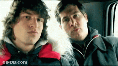 Two Men Are Sitting Next To Each Other In A Car Looking At The Camera . GIF