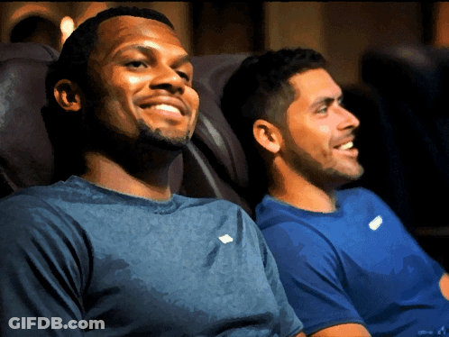 Two Men Are Sitting Next To Each Other In A Chair And Smiling GIF