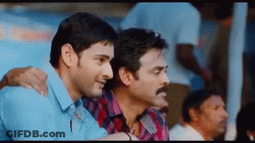 Two Men Are Sitting Next To Each Other In A Crowd Of People . GIF