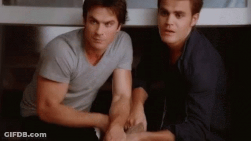 Two Men Are Sitting Next To Each Other In A Room Holding Hands . GIF